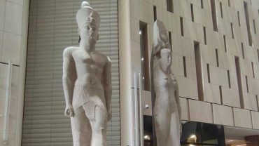 Two royal statues displayed on the grand staircase inside the Grand Egyptian Museum.