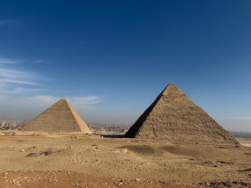 Vue panoramique sur les majestueuses pyramides de Gizeh sous un ciel bleu, un moment fort d'un voyage au Caire et dans une oasis de Siwa