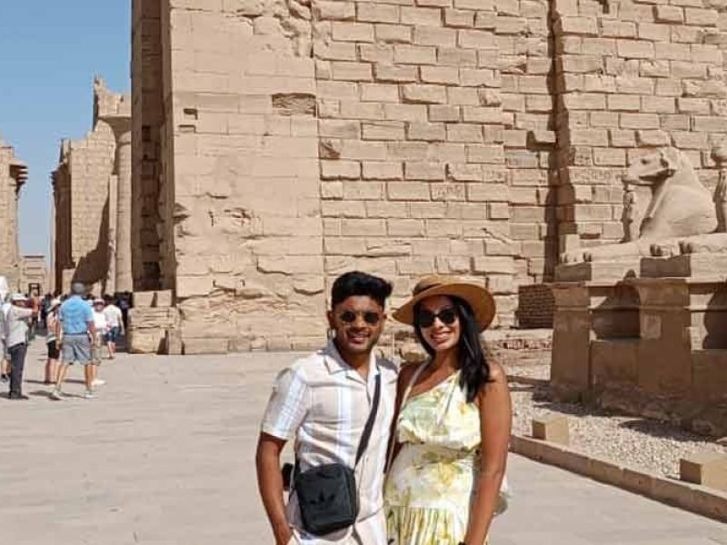 Un couple posant devant l'allée des sphinx à tête de bélier au temple de Karnak, une étape clé d'une journée à Louxor depuis Port de Safaga