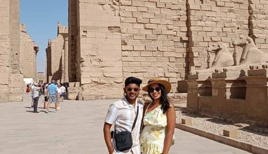 Un couple posant devant l'allée des sphinx à tête de bélier au temple de Karnak, une étape clé d'une journée à Louxor depuis Port de Safaga