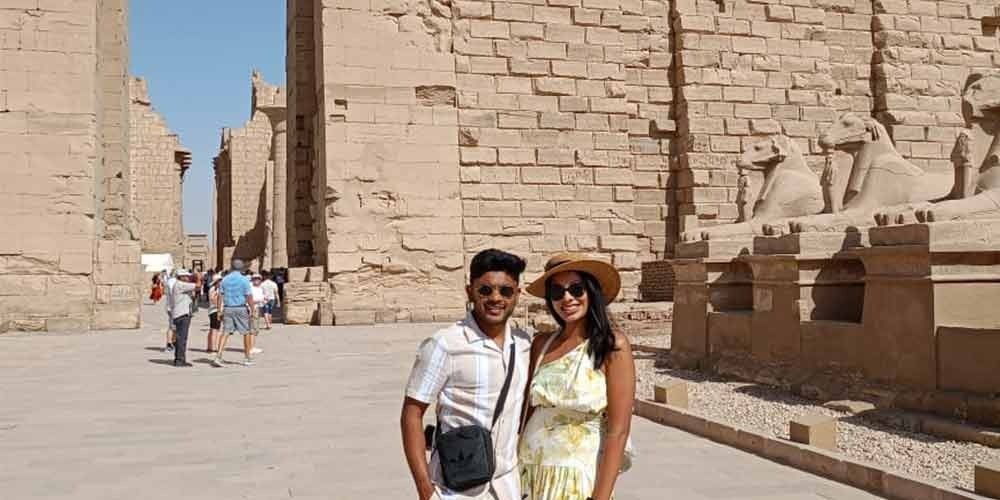 Un couple posant devant l'allée des sphinx à tête de bélier au temple de Karnak, une étape clé d'une journée à Louxor depuis Port de Safaga