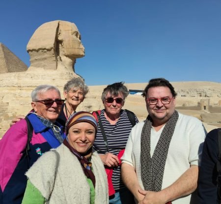 Un groupe de touristes souriants posant devant le Grand Sphinx de Gizeh lors d'une excursion organisée pour une journée depuis la porte de port Said au Caire et Sphinx