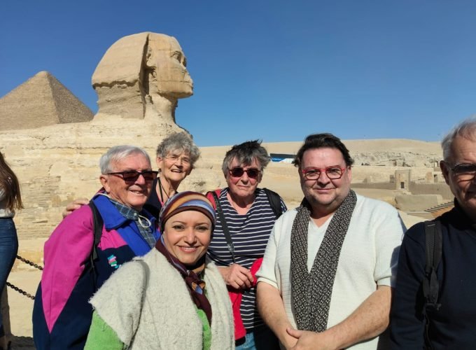Un groupe de touristes souriants posant devant le Grand Sphinx de Gizeh lors d'une excursion organisée pour une journée depuis la porte de port Said au Caire et Sphinx