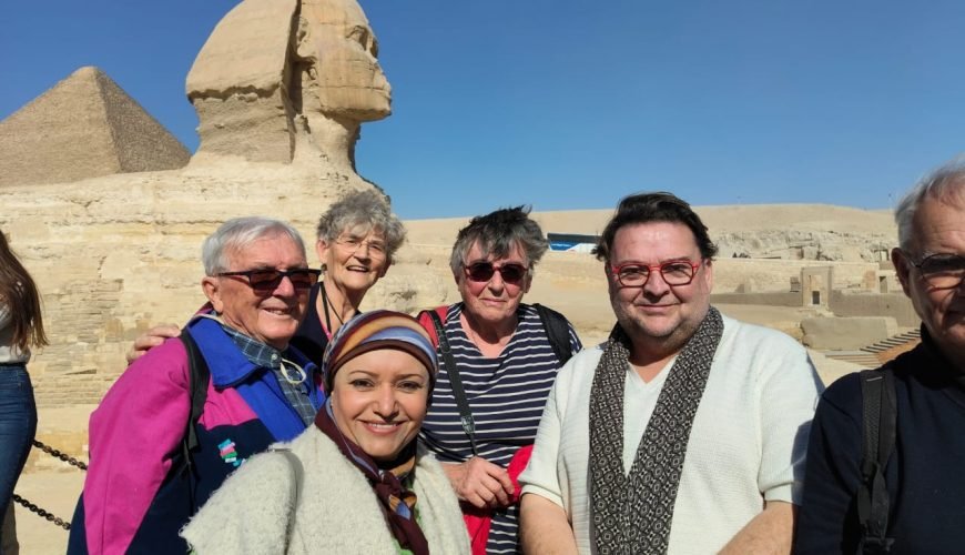 Un groupe de touristes souriants posant devant le Grand Sphinx de Gizeh lors d'une excursion organisée pour une journée depuis la porte de port Said au Caire et Sphinx