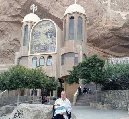 Une touriste posant devant l'entrée sculptée de l'église troglodyte de Saint-Simon au mont Mokattam lors d'une visite spéciale au Caire copte et à Khan el-Khalil