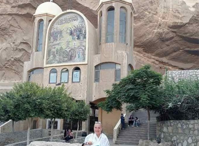 Une touriste posant devant l'entrée sculptée de l'église troglodyte de Saint-Simon au mont Mokattam lors d'une visite spéciale au Caire copte et à Khan el-Khalil