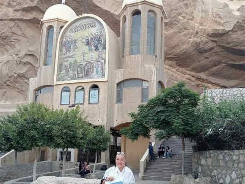 Une touriste posant devant l'entrée sculptée de l'église troglodyte de Saint-Simon au mont Mokattam lors d'une visite spéciale au Caire copte et à Khan el-Khalil