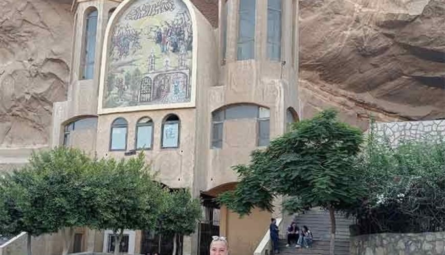 Une touriste posant devant l'entrée sculptée de l'église troglodyte de Saint-Simon au mont Mokattam lors d'une visite spéciale au Caire copte et à Khan el-Khalil