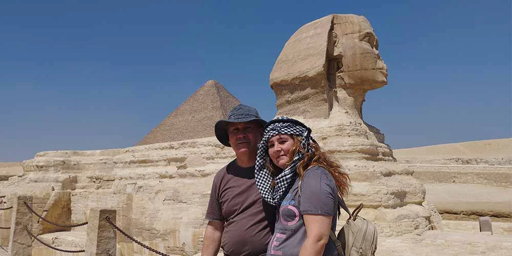 Una pareja tomando una foto frente a la Gran Pirámide y la Esfinge en Egipto