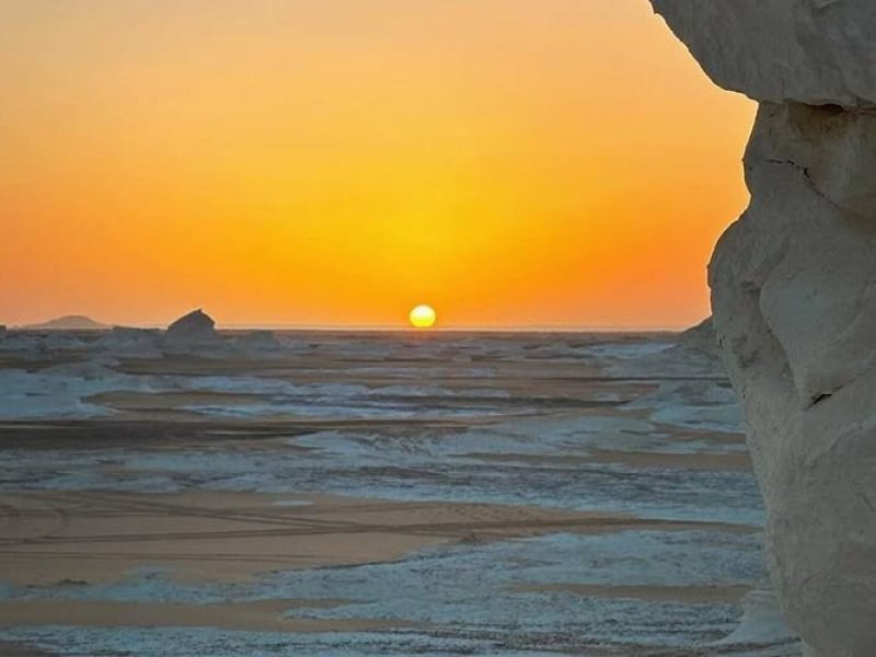 Vista panorâmica do Oásis de Bahariya com dunas e vegetação verde.