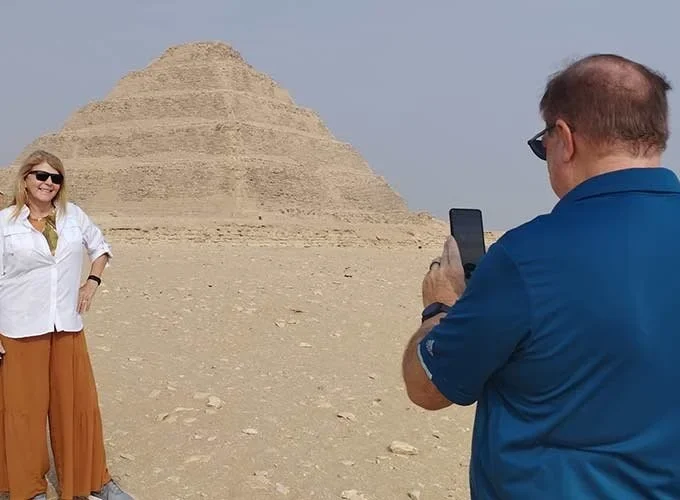 Un marido fotografía a su esposa frente a la Pirámide Escalonada de Saqqara.