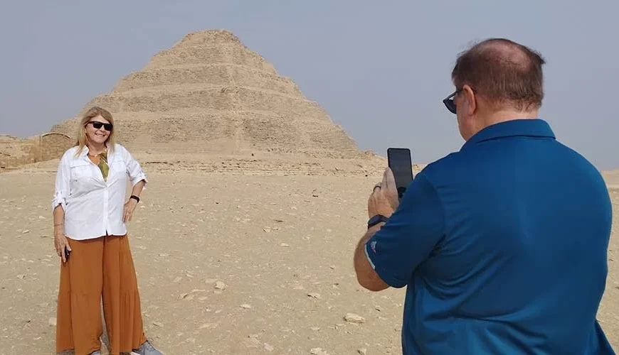 Un marido fotografía a su esposa frente a la Pirámide Escalonada de Saqqara.