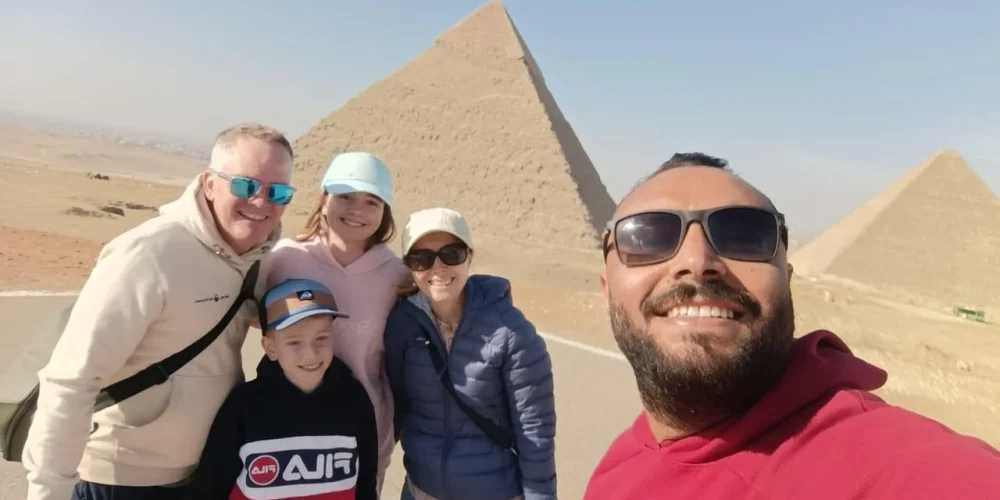 Una familia posa para una foto frente a las pirámides junto a su guía turística.