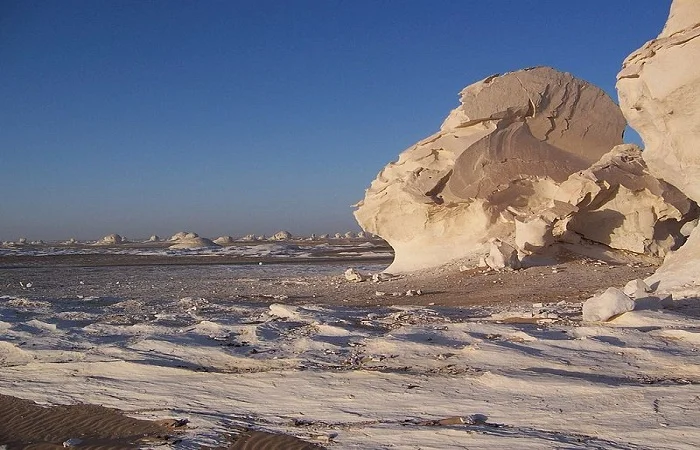 Roca blanca en el Desierto Blanco bajo un cielo colorido al atardecer.