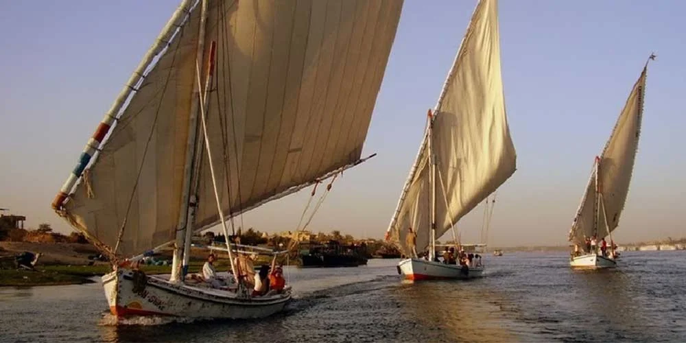 A felucca sailing on the Nile River at sunset with a stunning view