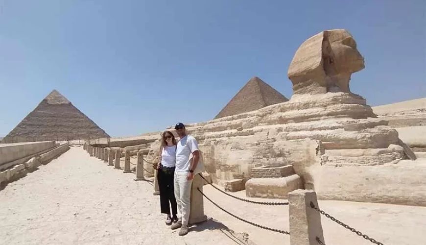 A couple taking a photo with the Great Sphinx of Giza and the Giza Pyramids