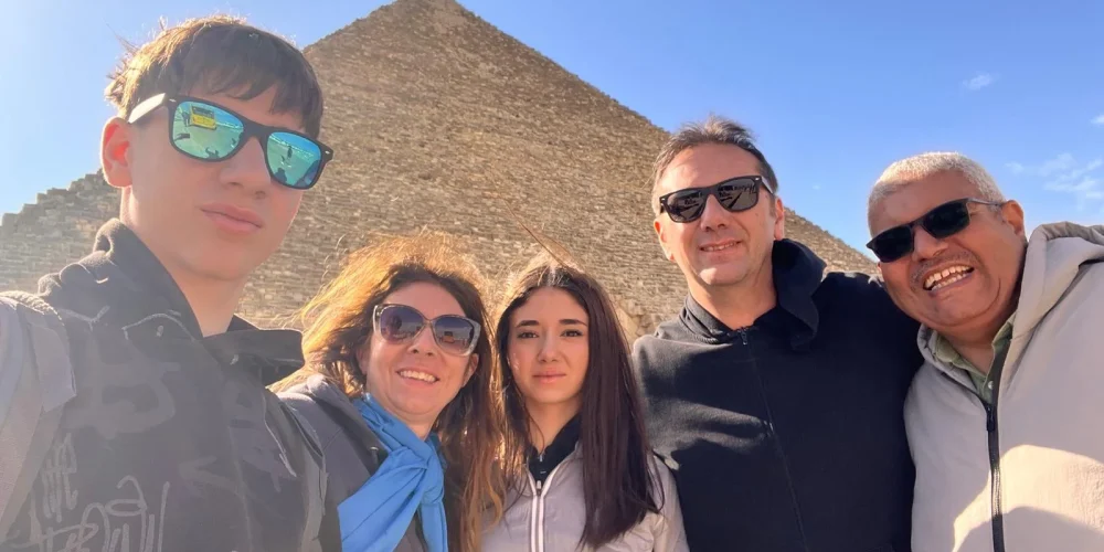 Una familia posa para una foto frente a las pirámides en la meseta de Guiza