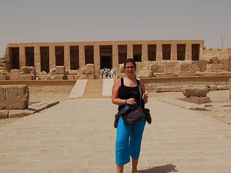 A tourist taking a photo outside the ancient Temple of Abydos, known for its impressive historic architecture