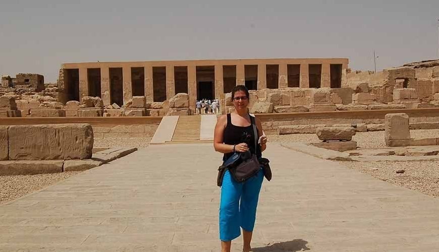 A tourist taking a photo outside the ancient Temple of Abydos, known for its impressive historic architecture