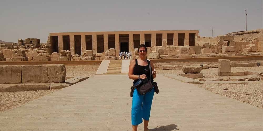 A tourist taking a photo outside the ancient Temple of Abydos, known for its impressive historic architecture