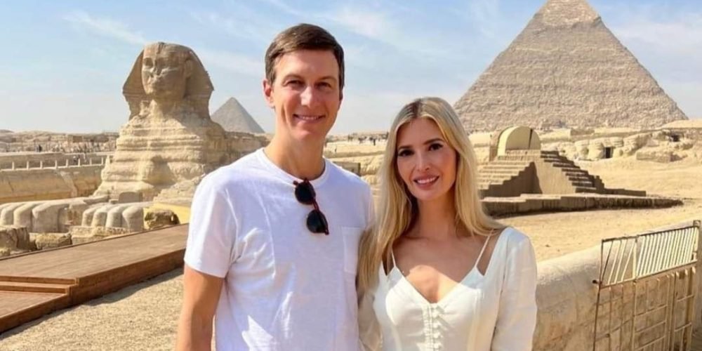 A man in a white t-shirt and a woman in a long white dress posing together in front of the Great Sphinx and a pyramid. The historical site is under a clear blue sky, showing the ancient limestone structures during an Egyptian Museum &Pyramids tour