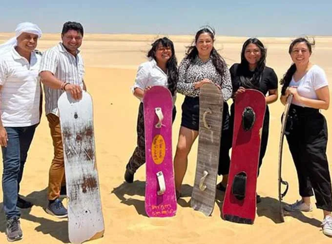 A group of people enjoying sandboarding on desert dunes in Fayum