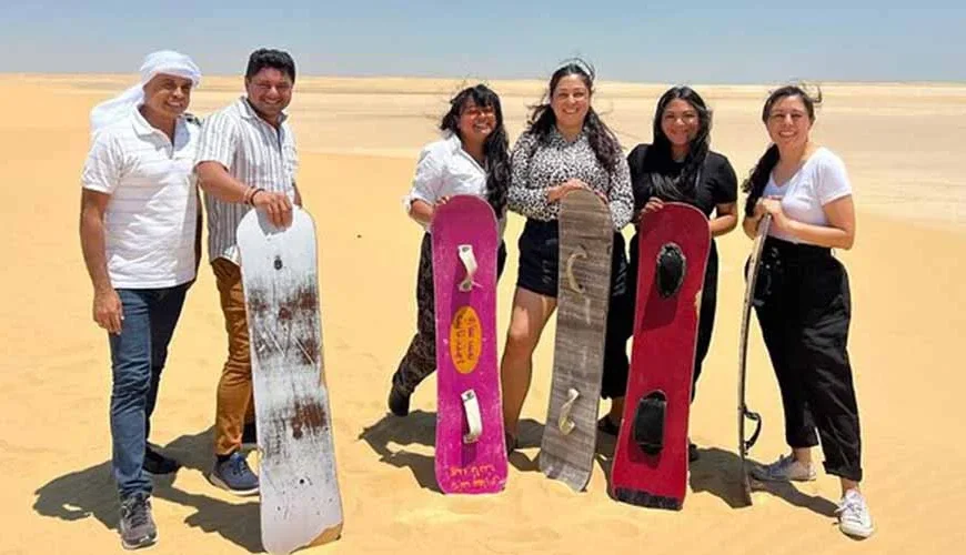 A group of people enjoying sandboarding on desert dunes in Fayum