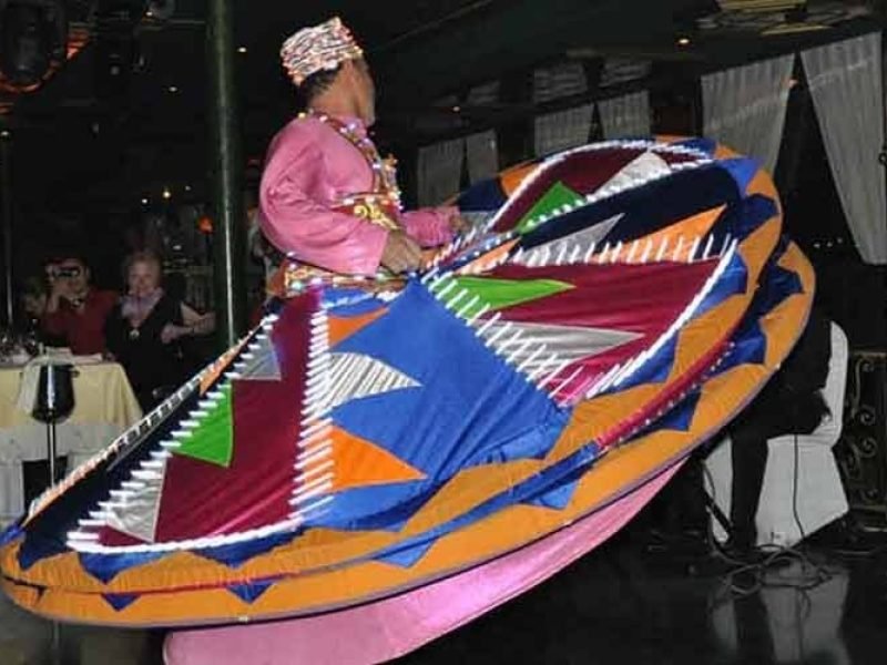Performers spinning colorful Tanura show during a dinner cruise