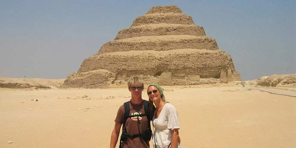 A couple taking a photo in front of the Step Pyramid of Saqqara