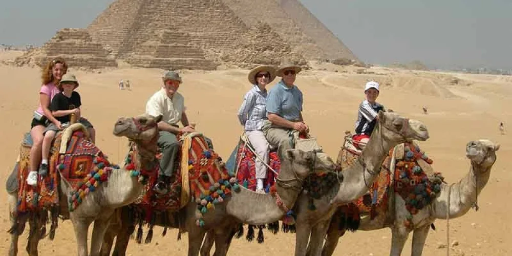 Family enjoying a camel ride in the area of Pyramids of Giza