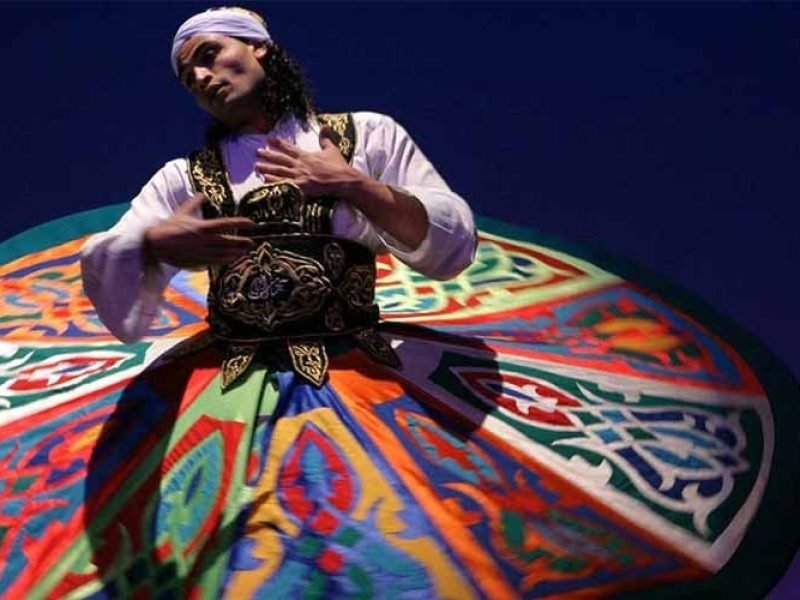 Cruzeiro navegando pelo rio Nilo com paisagens verdes, vilarejos e templos históricos ao fundo.