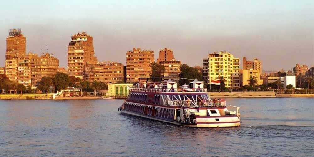 Passageiros aproveitando o convés durante um cruzeiro no rio Nilo ao pôr do sol.