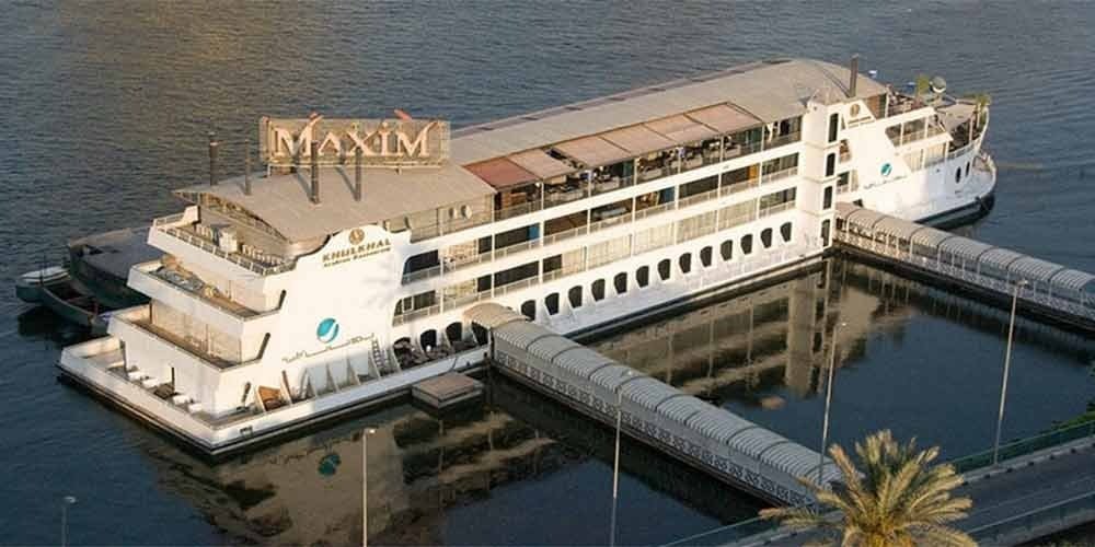 Passageiros aproveitando o convés durante um cruzeiro no rio Nilo ao pôr do sol.