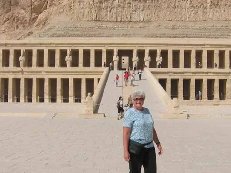 A female tourist taking a photo in front of the Temple of Hatshepsut.