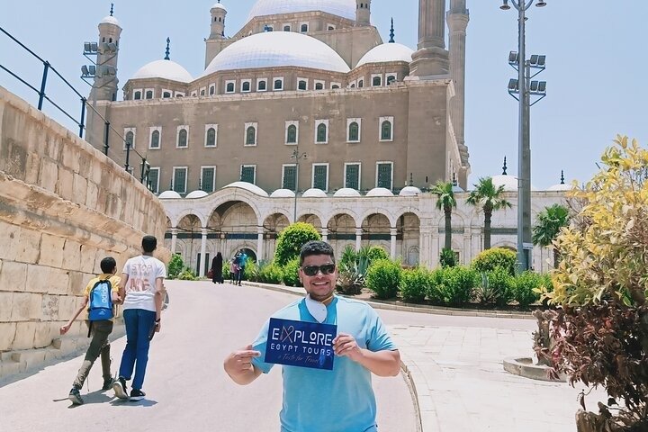 A tourist holding the company's sign in front of the Citadel of Saladin