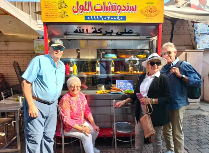 Group of friends taking a photo in front of a traditional Egyptian ful and falafel restaurant during their tour