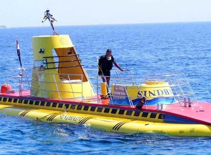 Turistas observando a vida marinha durante um passeio de submarino em águas cristalinas.
