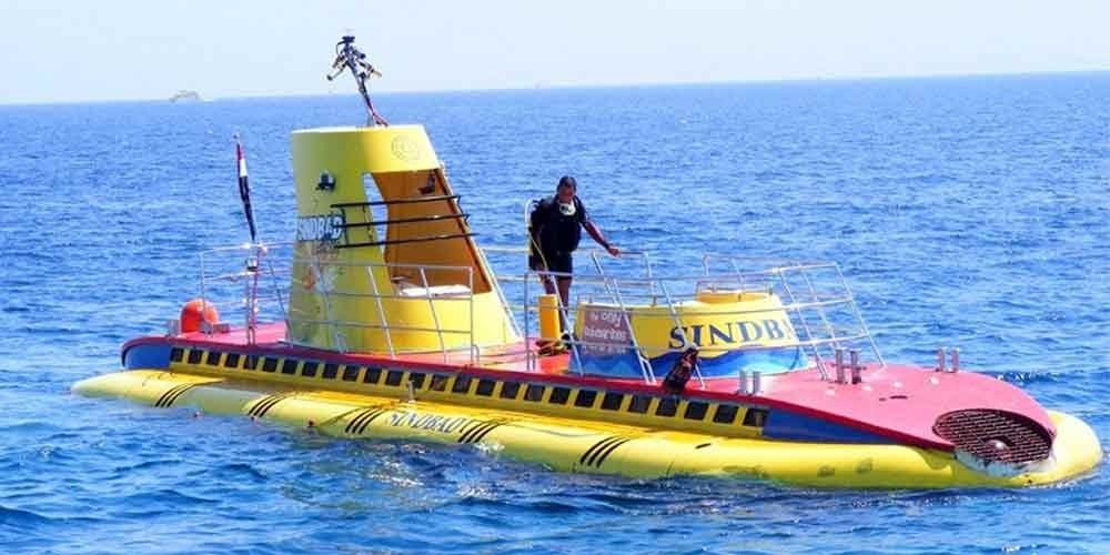 Turistas observando a vida marinha durante um passeio de submarino em águas cristalinas.