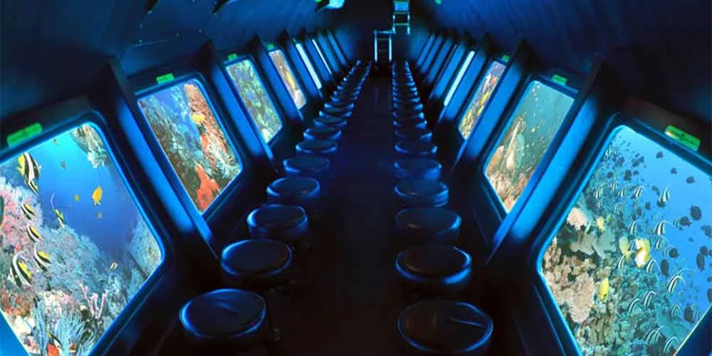 Interior view of a semi-submarine’s submerged observation deck with panoramic windows and swivel seats
