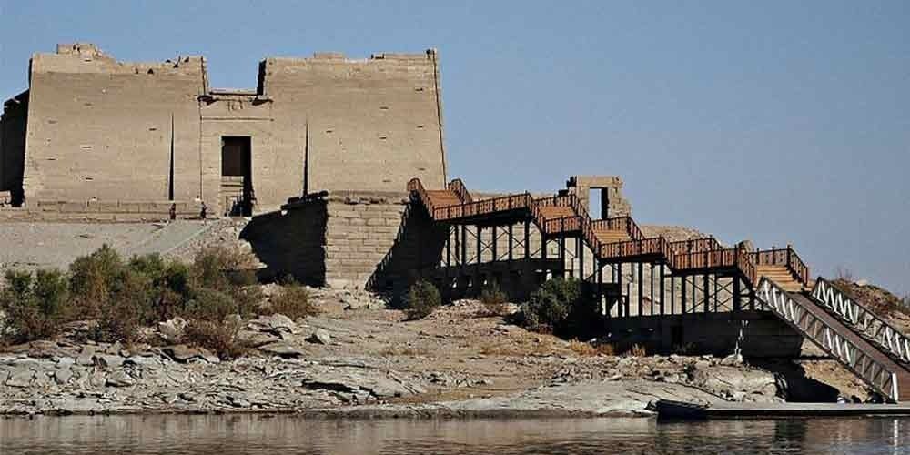 Fachada do Templo de Kalabsha às margens do Lago Nasser, com colunas e relevos visíveis.