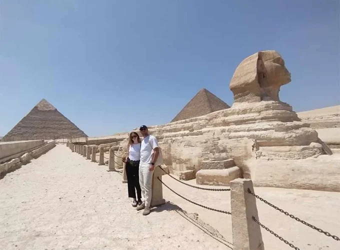 Una pareja se toma una foto frente a la Esfinge y las pirámides de Giza.