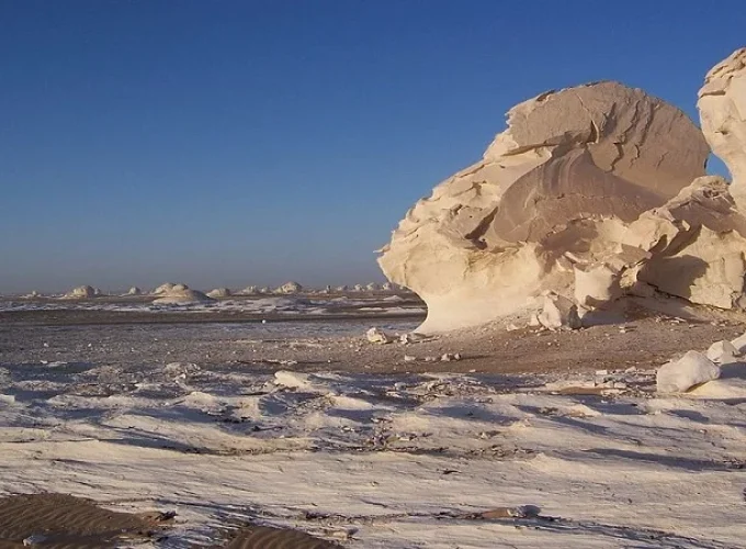 Roca blanca en el Desierto Blanco bajo un cielo colorido al atardecer.