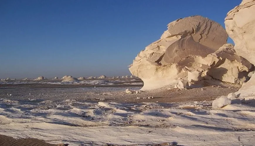 Roca blanca en el Desierto Blanco bajo un cielo colorido al atardecer.