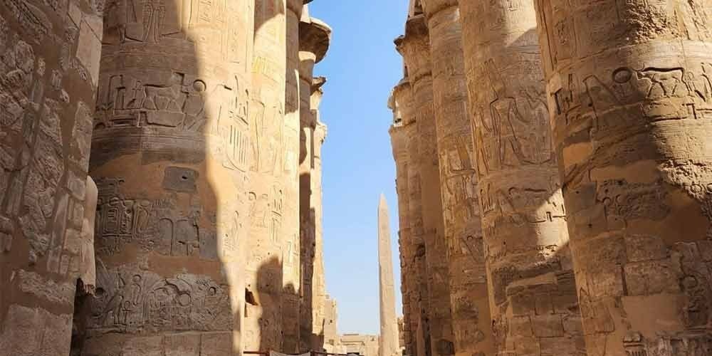 Les colonnes monumentales gravées de hiéroglyphes du temple de Karnak sous un ciel bleu, point fort d'une journée à Louxor depuis Port de Safaga