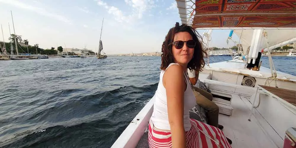 A tourist enjoying a felucca ride on the Nile River surrounded by fresh air and water