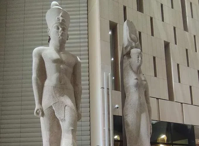 Two royal statues displayed on the grand staircase inside the Grand Egyptian Museum.