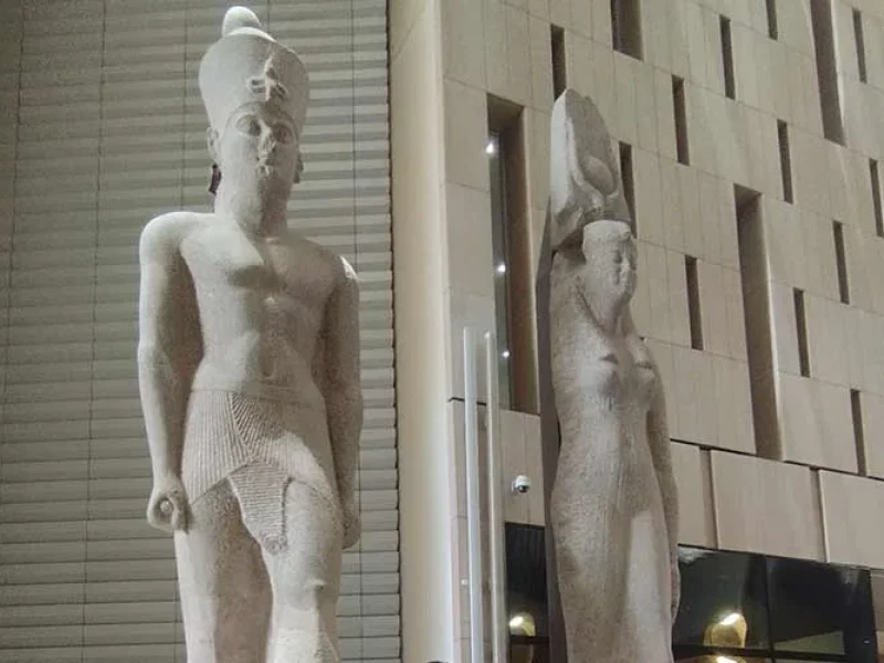 Two royal statues displayed on the grand staircase inside the Grand Egyptian Museum.