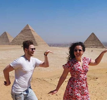 Un jeune couple faisant des poses rigolotes avec les pyramides en arrière-plan lors d'une Visite au Caire depuis Marsa Alam