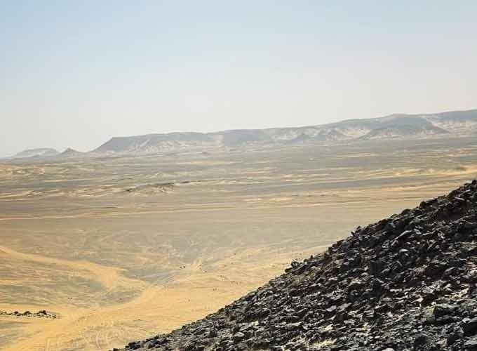 Dunas escuras do Deserto Negro sob um céu azul limpo.